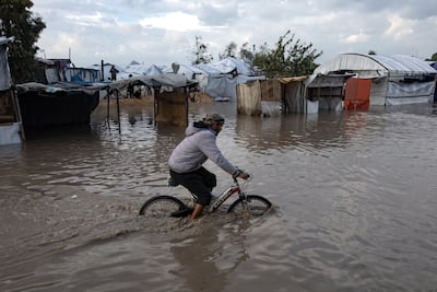 A Palestinian man cycles through a flooded street after heavy rain in Khan Younis, southern Gaza. EPA