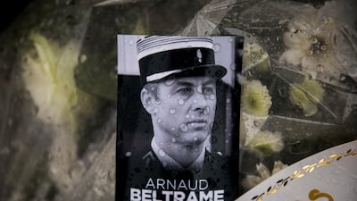 A photo of Lieutenant-Colonel Arnaud Beltrame placed on a bunch of flowers at the main gate of the police headquarters in Carcassonne, France. Emilio Morenatti / AP