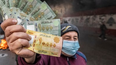 A man holds Lebanese pounds during a protest. The currency has plummeted by more than 90 per cent against the US dollar amid the deepening financial crisis. AP