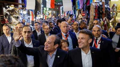 Mr El Sisi greets people as he walks alongside Mr Macron at Khan Al Khalili market in the Egyptian capital. Reuters