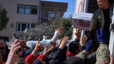 Residents receive food, clothes and household items from a lorry in Samandag, southern Turkey, 10 days after the earthquake. AFP