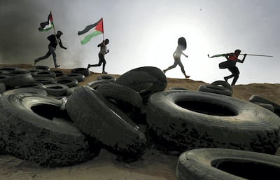 Palestinian protesters run during clashes with Israeli troops at Israel-Gaza border, in the southern Gaza Strip April 5, 2018. REUTERS/Ibraheem Abu Mustafa TPX IMAGES OF THE DAY
