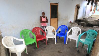 Musu L Kromah poses for a family portrait at her home in West Point, Monrovia, Liberia. The empty chairs are a representation of Musu’s parents and five other family members who died of the Ebola virus during an outbreak of the disease in 2014. Ahmed Jallanzo / EPA