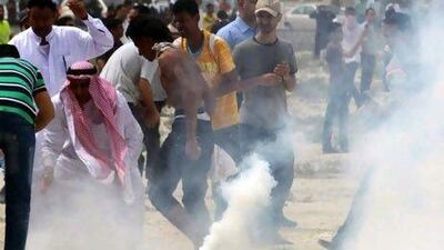 Anti-government protesters bury tear gas canisters fired by riot police Sunday, AP Photo/Hasan Jamali
