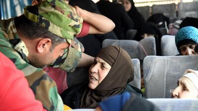 A soldier loyal to Syria's President Bashar Al Assad talks to a woman in a bus after they were released by militants from Idlib, Syria May 1, 2018. SANA / Handout via Reuters