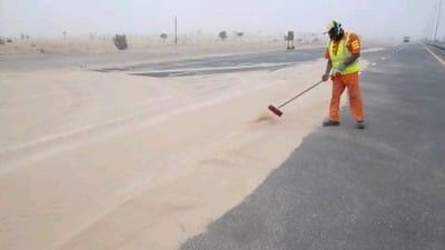A worker clears sand from the Jabel Ali - Lahbab road after the weekends sandstorms.