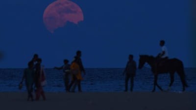 A man rides a horse past people watching the supermoon rise at Marina Beach in Chennai. Arun Sankar / AFP Photo