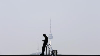 A man using his mobile phone is silhouetted against the backdrop of N Seoul Tower, commonly known as Namsan Tower, in Seoul. Kim Hong-Ji / Reuters