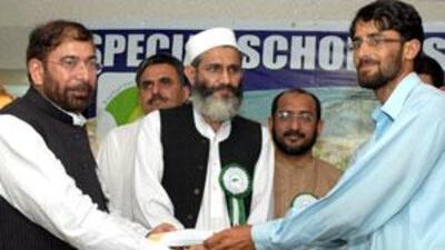 A university representative from Pakistan's disturbed areas, receives cash award from Riaz Farooq, left, the president of the Pak Association Dubai.