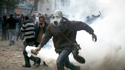 A protester prepares to throw a tear-gas canister at Egyptian riot police near the interior ministry during clashes in Cairo on Sunday. Thousands of demonstrators demanded the ruling military quickly announce a date to hand over power to an elected government. Tara Todras-Whitehill / AP Photo