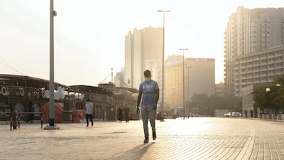 People walk by Dubai Creek in Deira. Buildings create shade that keep temperatures down. Reem Mohammed / The National