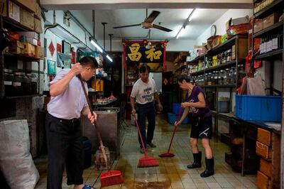 Shop owners clean their stores in Macau. Isaac Lawrence / AFP