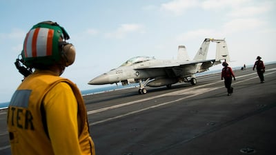A crew member looks at a F/A-18 fighter jet on the deck of the USS Abraham Lincoln aircraft carrier in the Arabian Sea. AP