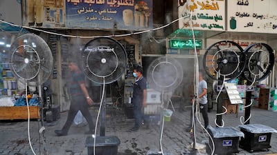Pedestrians in Baghdad enjoy the cooling spray from fans blowing air mixed with water into a Baghdad street during a heat wave.