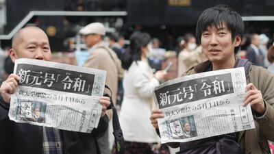 People hold up local papers reporting the announcement of the new era name "Reiwa" in Tokyo, April 1, 2019. AFP