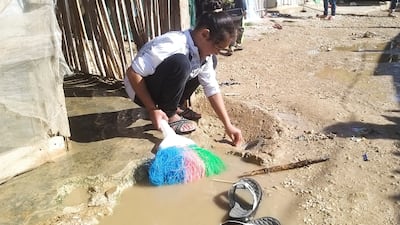 A Syrian refugee girl uses a broom near tents at an informal tented settlement in Akkar, Lebanon. Reuters