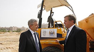 Manchester City manager Mark Hughes, left, with the club's chief executive Garry Cook at the new football pitch and City's official training headquarters in Abu Dhabi yesterday.