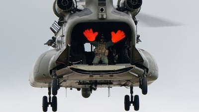 A crew member waves to the crowd from a Chinook during the Royal International Air Tattoo at RAF Fairford, Gloucestershire. PA