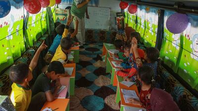 Displaced Syrian children take lessons on a bus converted into a classroom.