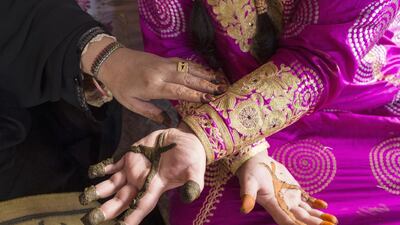 A mother removes henna from her daughter’s hand at the henna stall. Reem Mohammed / The National