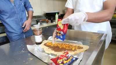 Abdulsalam Mohammed, 31, from India, prepares a Nutella regag sandwich with spicy Chips Oman crisps, said by many to be the pinnacle of Nutella sandwiches, at Abu Dhabi’s Al Dhifa cafeteria near Airport Road. Fatima Al Marzooqi / The National