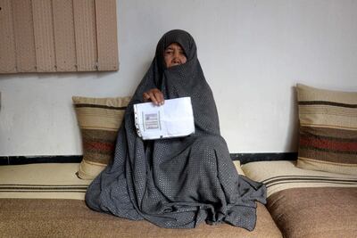Fatimah, 55, poses for a picture as she holds her ID card or Tazkira registered to vote in the upcoming parliamentary election, at her House in Mazar-i-Sharif. AFP