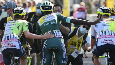 Intermarche-Wanty's Biniam Girmay, wearing the sprinter's green jersey, is assisted across the finish line by teammates after crashing near the end of the race. AFP