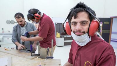 Omar Al Marzooqi installs hinges on a wooden plank