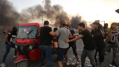 Iraqi protesters assist a wounded comrade in Baghdad. AFP