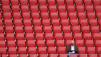 A man wearing a face mask sits in the stands before the match. Reuters