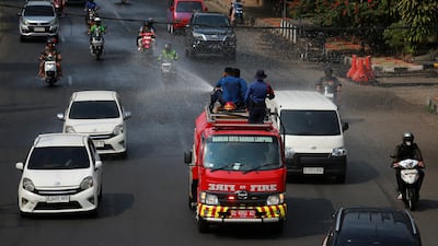 Firefighters spray water to clear volcanic ash following the eruption. Reuters