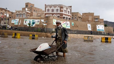 A Yemeni pushes a wheelbarrow through a flooded street following heavy rains in the old quarter of Sana'a, Yemen. EPA
