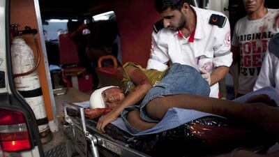 Bassam Ali Sayma, a paramedic that works for Gaza's Red Crescent with an injured boy as they arrive at Shifa Hospital in Gaza City on July 11. The child suffered shrapnel wounds from an Israeli air strike near his home in Nussarat, Gaza. Heidi Levine for The National