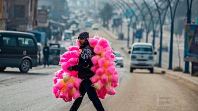 A street vendor selling cotton candy crosses a road in the northern Syrian city of Raqa, the former Syrian capital of ISIS. The Kurdish-led Syrian Democratic Forces overran Raqa in 2017, after years of what residents described as ISIS' brutal rule, which included public beheadings and crucifixions. AFP