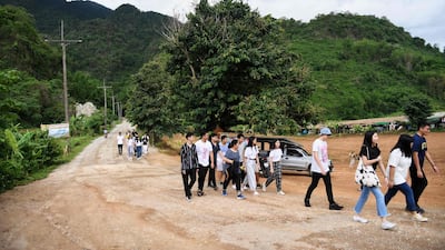 Visitors walking down the road away from the Tham Luang cave, where 12 boys from the "Wild Boars" football team and their coach were trapped last year, in the Mae Sai district of Chiang Rai province. AFP