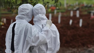 Family members watch workers bury a Covid-19 victim at the Padurenan cemetery in Bekasi, West Java, Indonesia. AP Photo
