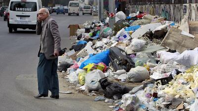 A Lebanese man covers his nose from the smell as he passes by a pile of garbage on a street in Beirut, Lebanon. Bilal Hussein / AP Photo