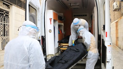 Three members of the White Helmet pick up two bodies at Idlib’s al-Ziraa hospital before bringing them to the cemetery.