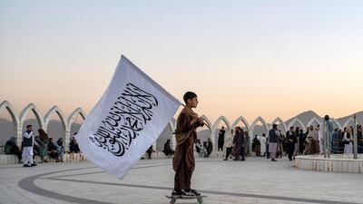 A young skateboarder carries the Taliban flag across a hilltop in Kabul, Afghanistan. AFP