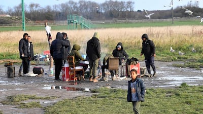 Migrants keep themselves warm next to a fire at camp in Calais, northern France. (Photo by FRANCOIS LO PRESTI / AFP)
