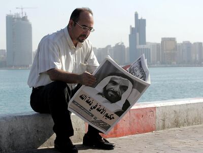 A man reads a newspaper with Sheikh Zayed on the front page during the day after his death. Rabih Moghrabi / AFP