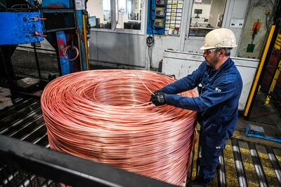 An employee monitors the 8mm diameter copper cable which is rolled up before passing through a rolling mill to become cable at the Nexans manufacture in Lens, northern France. (Photo by Denis Charlet / AFP)