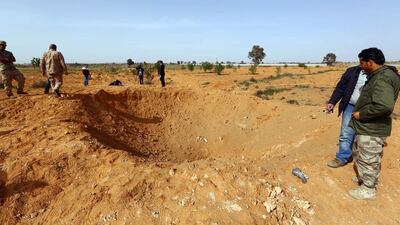 Members of the Libya Dawn stand by a crater on the ground following a reported air raid by Libyan pro-government forces in Tarhuna, 80 kms south-east of Tripoli (AFP PHOTO / MAHMUD TURKIA)