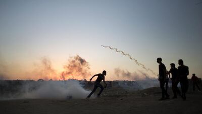 Palestinian protesters run for cover from tear gas fired by Israeli soldiers during clashes on the Israeli border with Gaza in Buriej, central Gaza Strip. Khalil Hamra / AP Photo