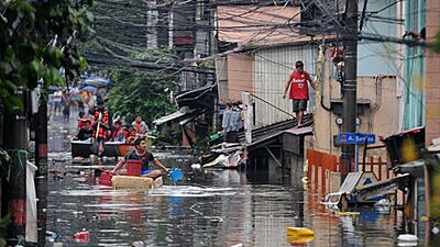 A man floats down a flooded street in Manila today.
