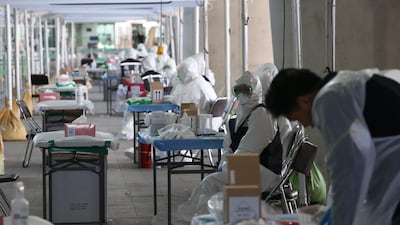 Medical workers wearing protective gear wait for foreign passengers to take samples at an 'Open Walking-Thru' centre for coronavirus Covid-19 tests at the airport in Incheon. EPA