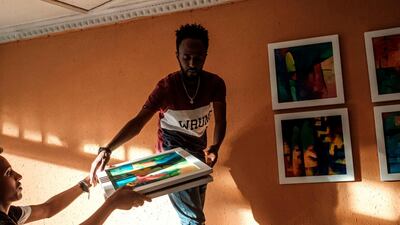 A person hands framed paintings to Eritrean painter Noah Mulubrhan as he prepares an exhibition in a local coffee shop in Addis Ababa. AFP