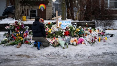 A man kneels at a memorial for Renee Nicole Good near the site of her shooting in Minneapolis, Minnesota. AFP