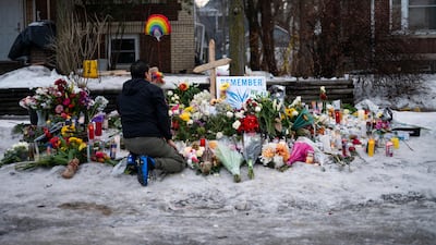 A man kneels at a memorial for Renee Good near the site of her shooting. Getty Images