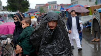 A boy covers himself with a plastic sheet to shelter from the rain in Kabul, Afghanistan. AP
